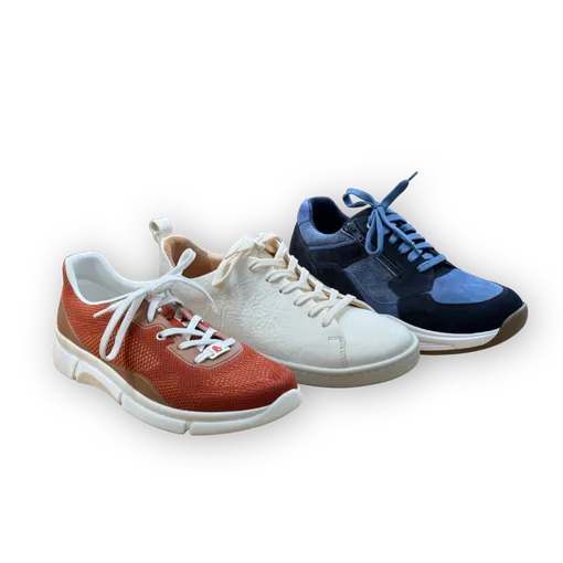 Drei Sneaker unterschiedlicher Farbe aufgereiht stehend.